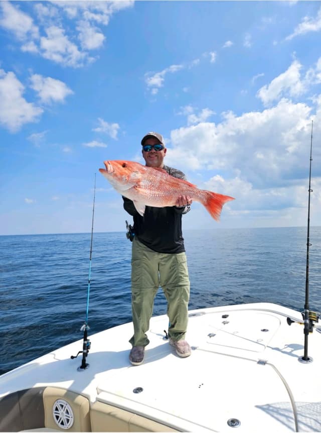 Richard, a My Reseller Genie customer, holding a fish on a boat